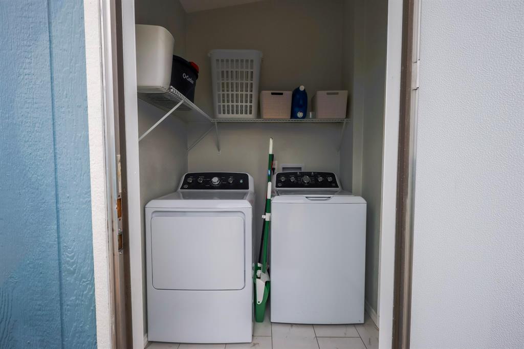 Laundry alcove featuring white tile flooring and overhead wire shelving