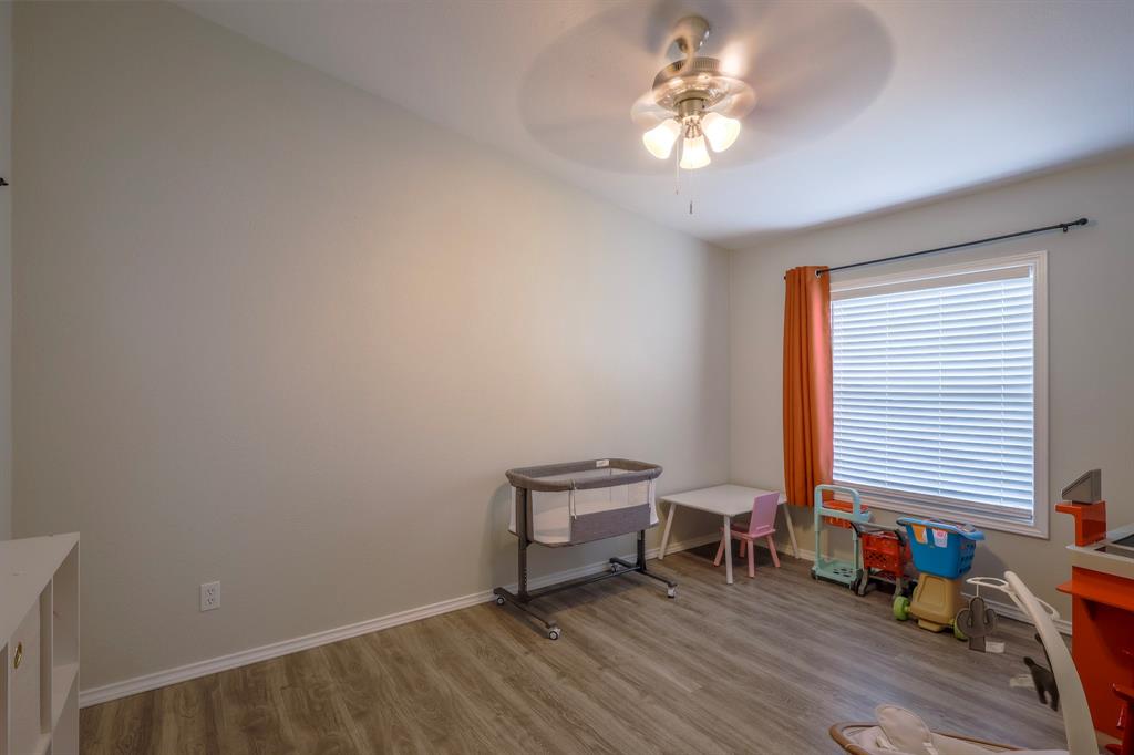 Room featuring vaulted ceilings, wood-finish flooring, a multi-blade ceiling fan with light fixture, and a window with horizontal blinds