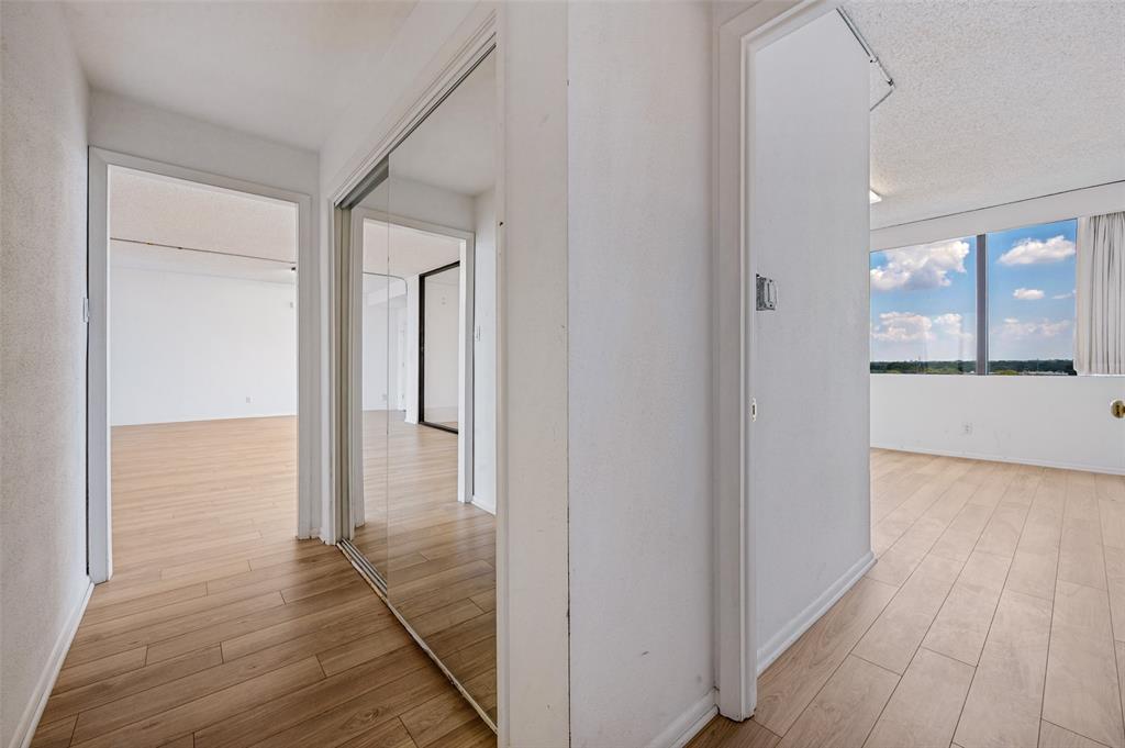 Interior featuring wood-finish flooring, sliding mirror-panel closet doors, and floor-to-ceiling windows