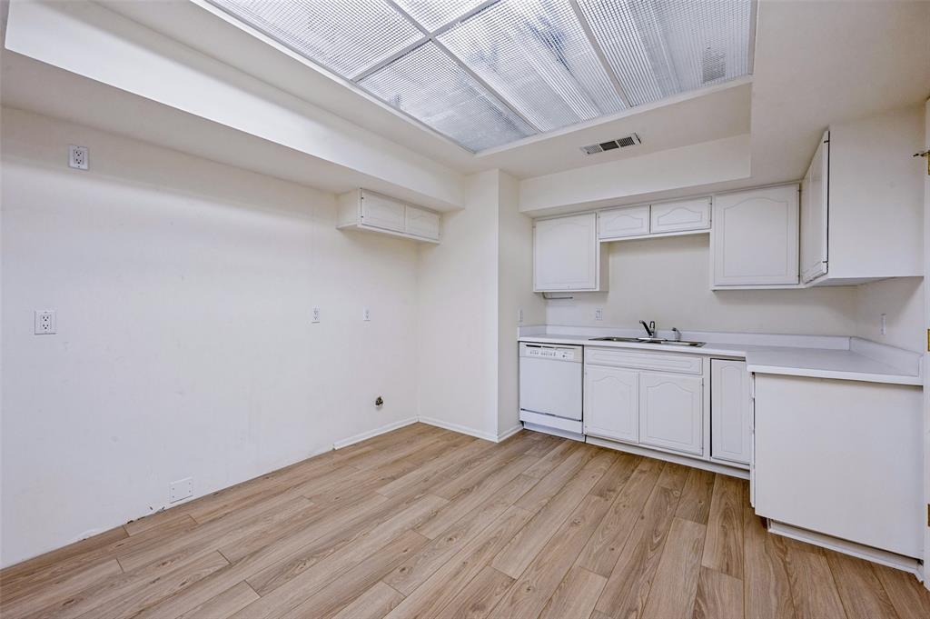 Kitchen featuring white cabinetry, wood-finish flooring, a stainless steel sink with a high-arch faucet, a built-in dishwasher, and a recessed ceiling light panel