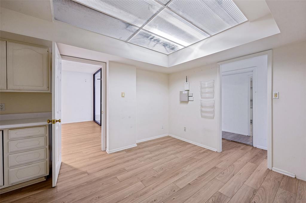 Interior space featuring wood-finish flooring, a recessed ceiling panel with integrated lighting, and white built-in cabinetry