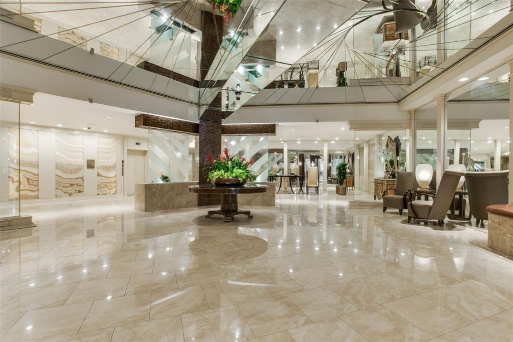 Grand lobby featuring polished stone tile flooring, mirrored ceiling accents, recessed lighting, and ornate decorative stone wall panels