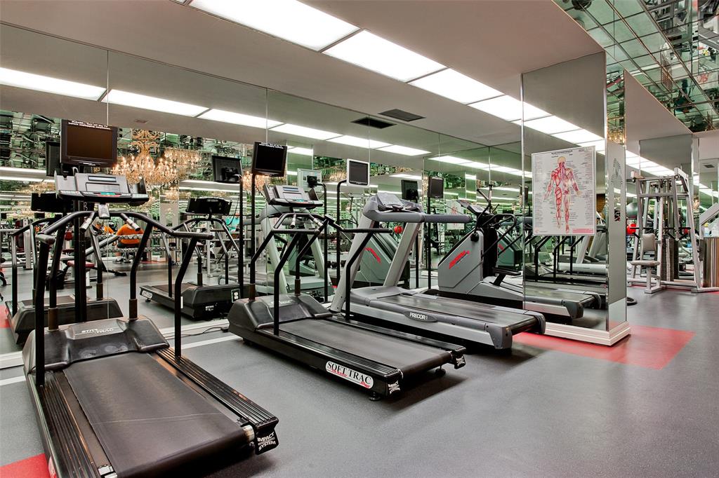 Fitness room featuring full-wall mirrored surfaces, recessed ceiling lighting, and resilient composite flooring
