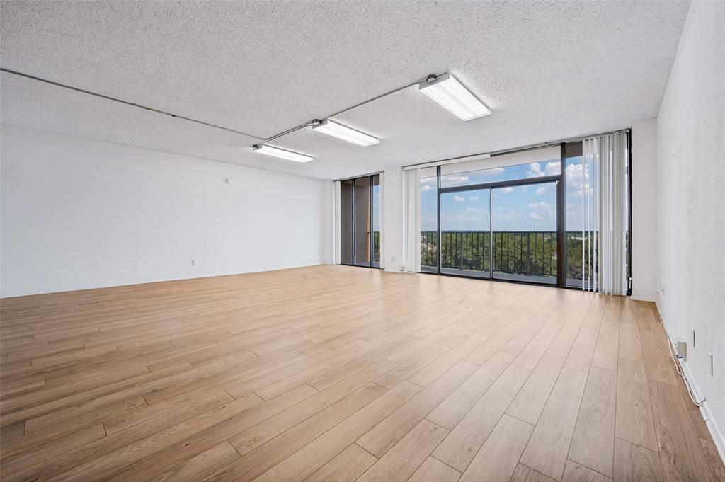Expansive living area featuring wood-finish flooring, sliding glass doors, floor-to-ceiling windows, and linear track lighting