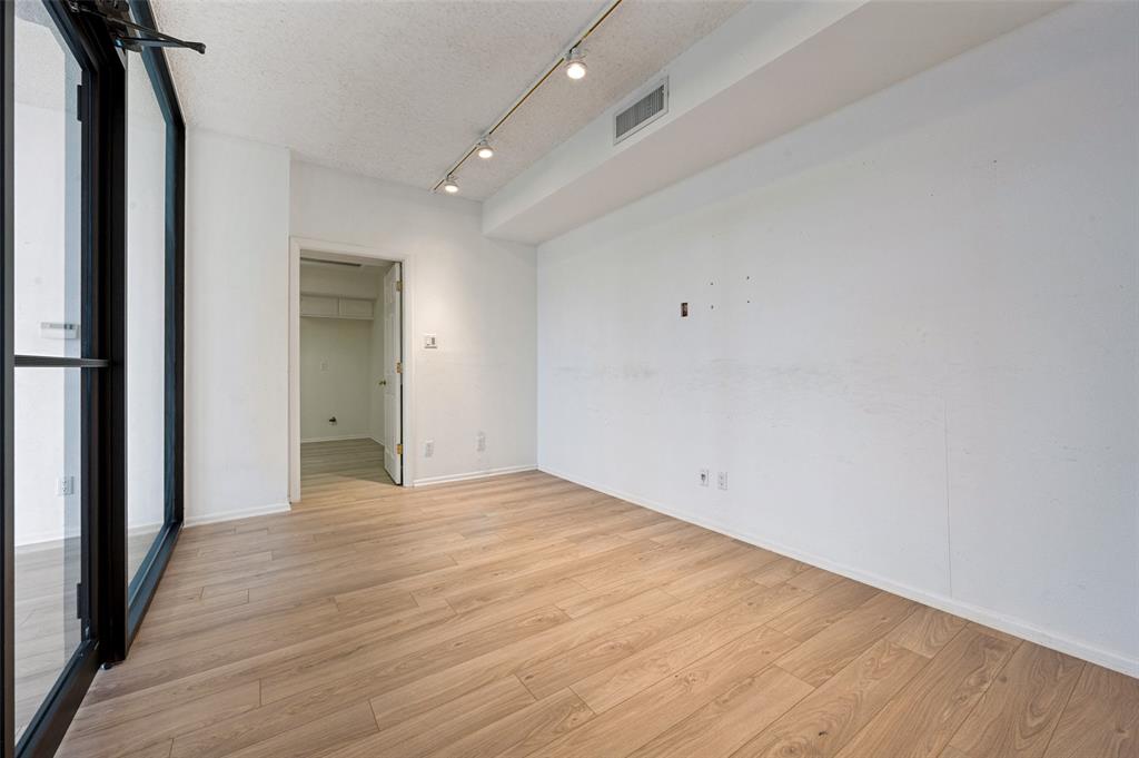 Wood-finish flooring, floor-to-ceiling black-framed glass paneling, and adjustable directional track lighting