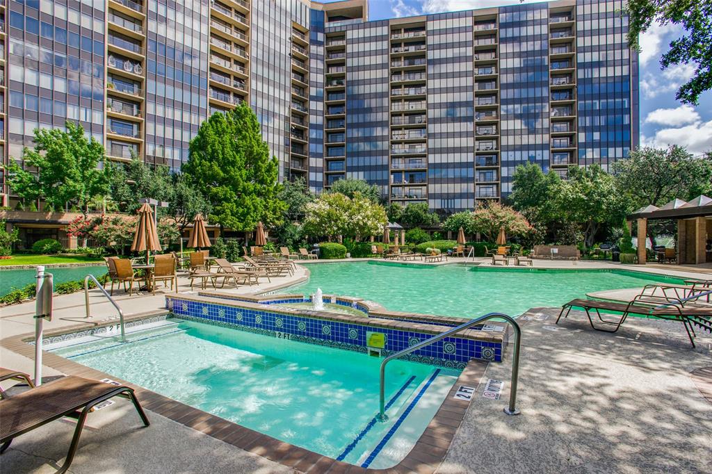 Swimming pool featuring a raised hot tub with decorative tile inlay, aggregate concrete decking, and mature landscaping Swimming pool featuring a raised hot tub with decorative tile inlay, aggregate concrete decking, and mature landscaping