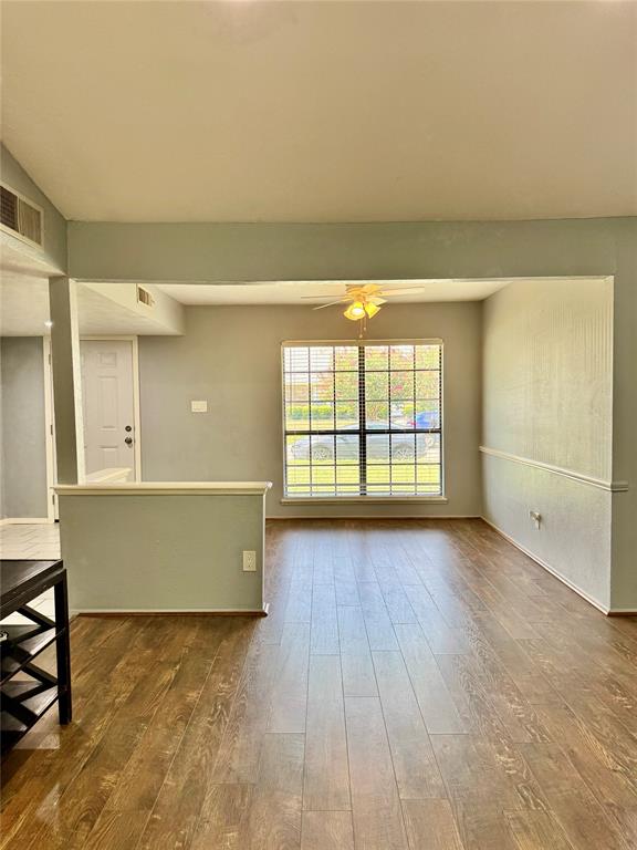 Wood-finish flooring, grid-pattern window, chair rail molding, ceiling-mounted light fixture, and half-wall divider