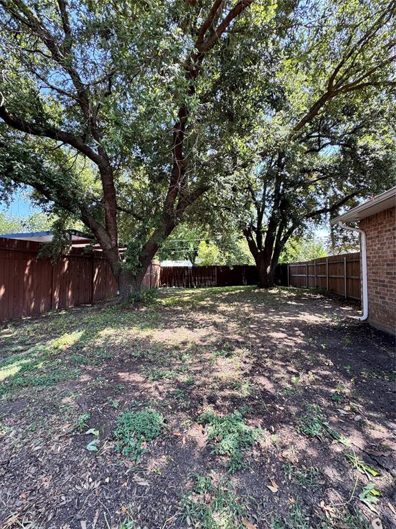 Backyard featuring mature trees, and a full-height wood perimeter fence.