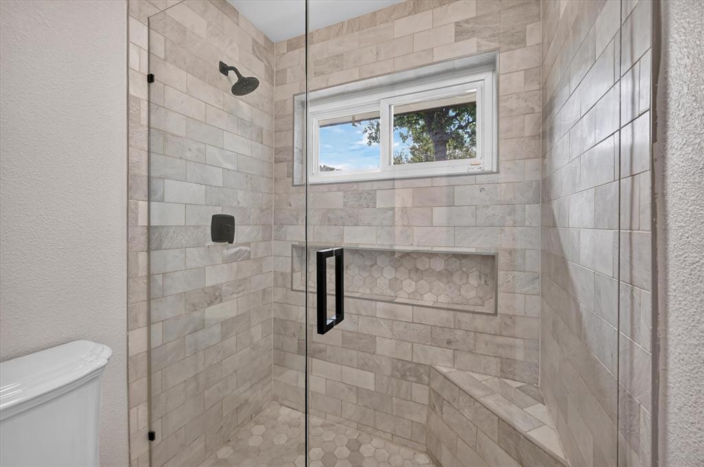 Downstairs ensuite surrounds, hexagonal tile flooring, a built-in bench, recessed shower niche, and matte black hardware