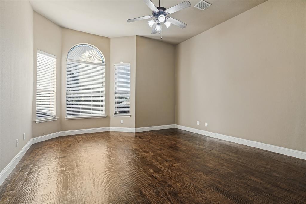Room featuring wood-finish flooring, a bay window with an arched transom, and a ceiling fan with integrated lighting
