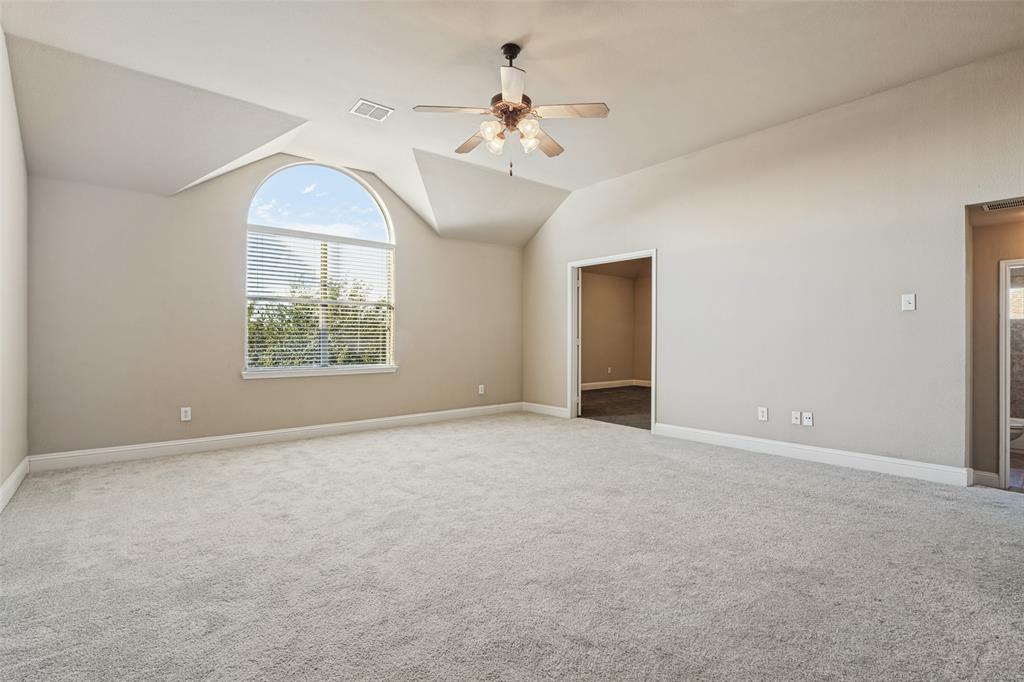 Vaulted ceilings featuring an arched window, neutral wall coloring, and a central ceiling fan with integrated lighting