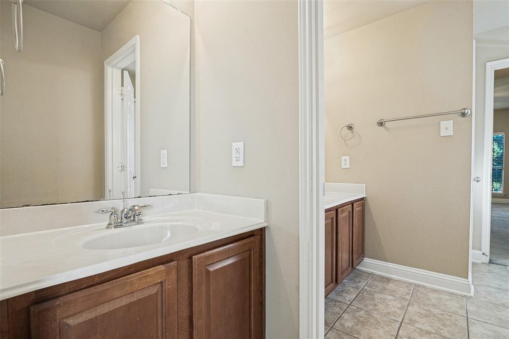 Dual vanity area featuring wood-finish cabinetry, white solid-surface countertops with integrated sinks, polished chrome hardware, and large wall-mounted mirrors