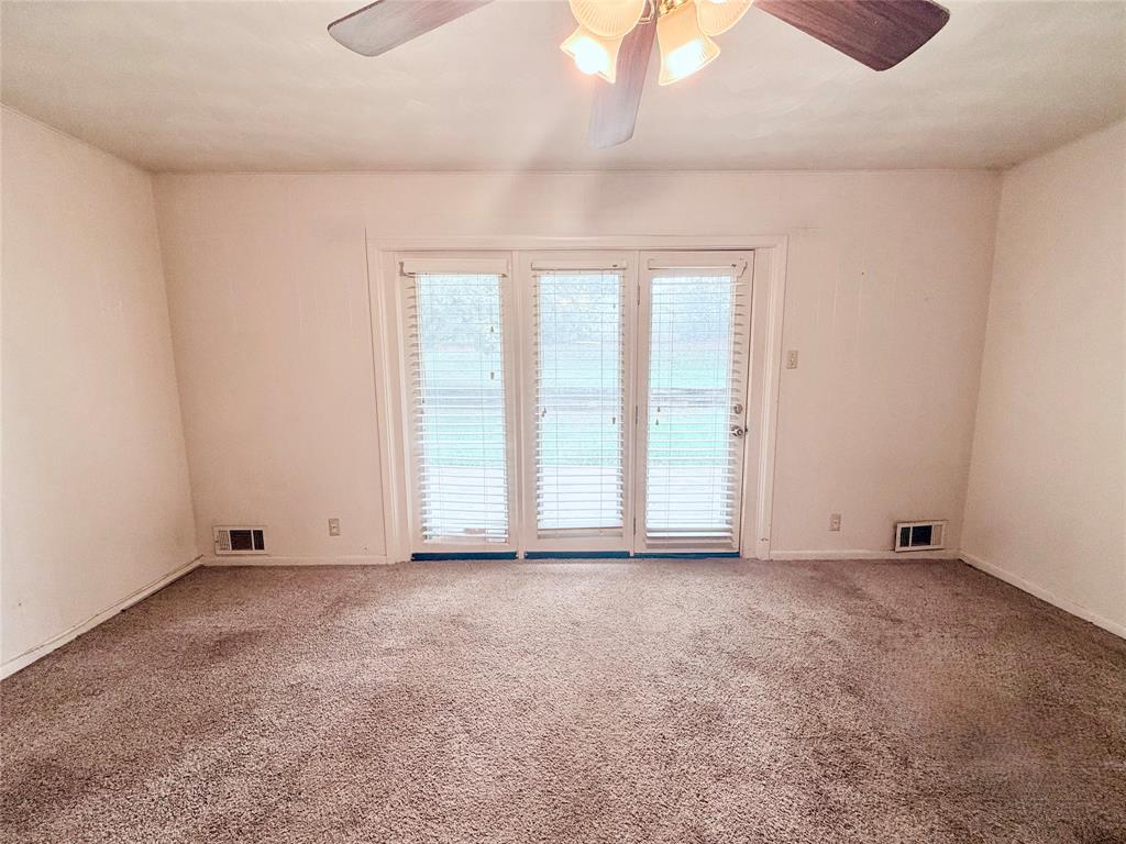 Triple-pane glass patio doors featuring integrated blinds, wall-to-wall carpeting, and a ceiling-mounted light fixture with a fan