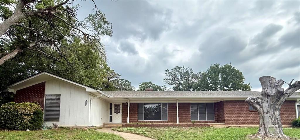 Single-story ranch exterior featuring a mixed brick and vertical siding facade, covered front porch, and expansive windows