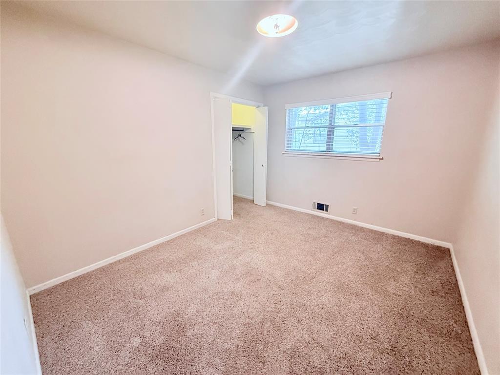 Neutral-toned interior featuring wall-to-wall carpeting, a reach-in closet with double doors, and a double-hung window