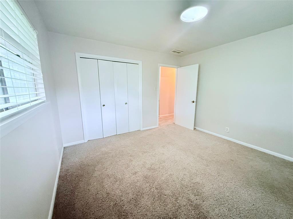 Neutral wall color, carpeted flooring, bi-fold closet doors, and horizontal slat window blinds