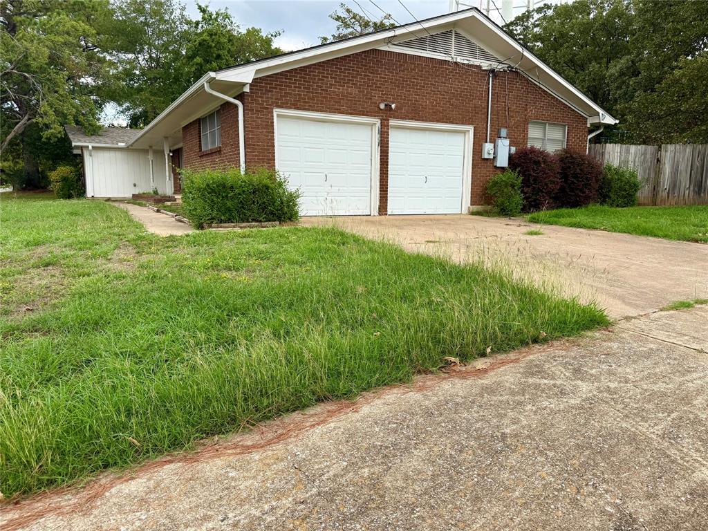 Brick exterior featuring a dual-bay garage, concrete driveway, and gabled roofline