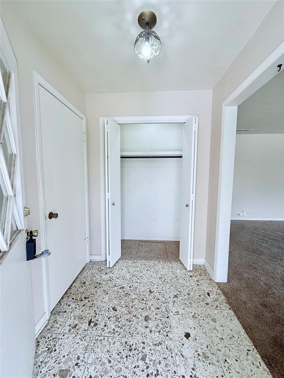 Entryway featuring terrazzo flooring, a multi-panel door with decorative glass inlay, and a built-in closet with double bifold doors