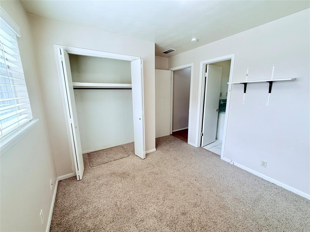 Neutral wall-to-wall carpeting, closet with built-in shelving, white-finished interior doors, and wall-mounted shelving unit