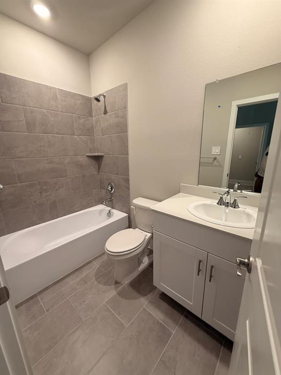 Bathroom featuring a vanity with an integrated basin, large format tile flooring, a shower-tub combination with horizontal wall tile surround, and a wall-mounted mirror