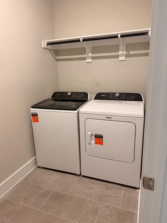 Laundry area featuring large-format ceramic tile flooring and a wall-mounted white shelving unit with an integrated hanging rod