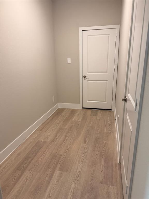 Neutral-toned interior space featuring wood-finish flooring and two-panel interior doors with satin nickel hardware