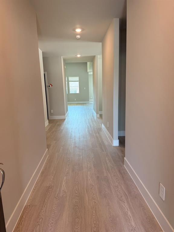Hallway featuring neutral wall tones, wood-finish flooring, and recessed ceiling lighting