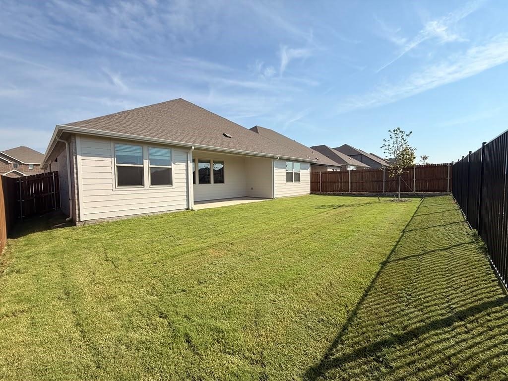 Rear exterior featuring a covered patio, horizontal siding, and a fenced-in lawn area