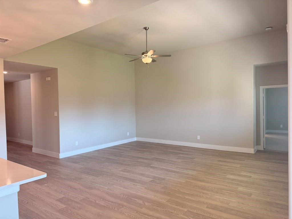 Vaulted ceilings, wood-finish flooring, and a central ceiling fan fixture