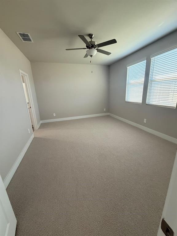 Neutral-toned carpeted room featuring wall-to-wall carpeting, a multi-blade ceiling fan with a center light fixture, and dual windows with horizontal blinds