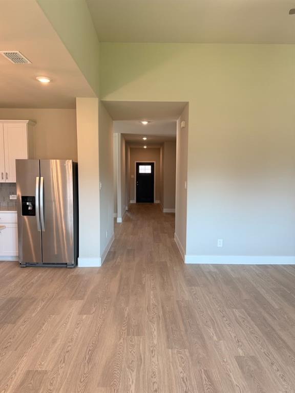 Open-concept kitchen area featuring wood-finish flooring, recessed lighting, and stainless steel refrigerator