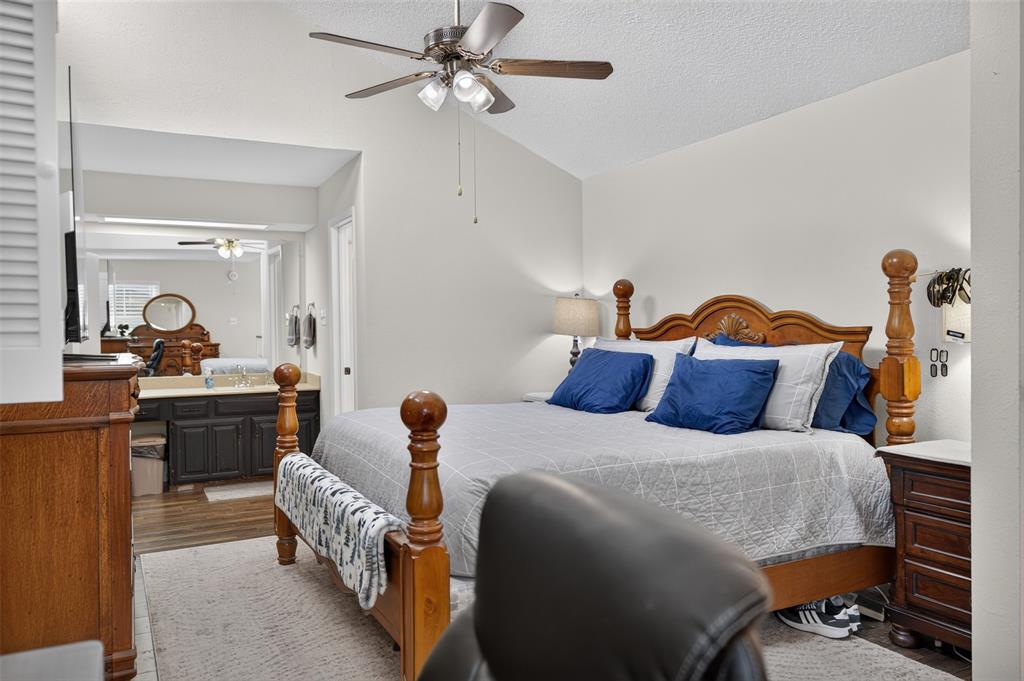 Vaulted ceiling featuring a ceiling fan with light kit, and a vanity area equipped with dark-finish cabinetry