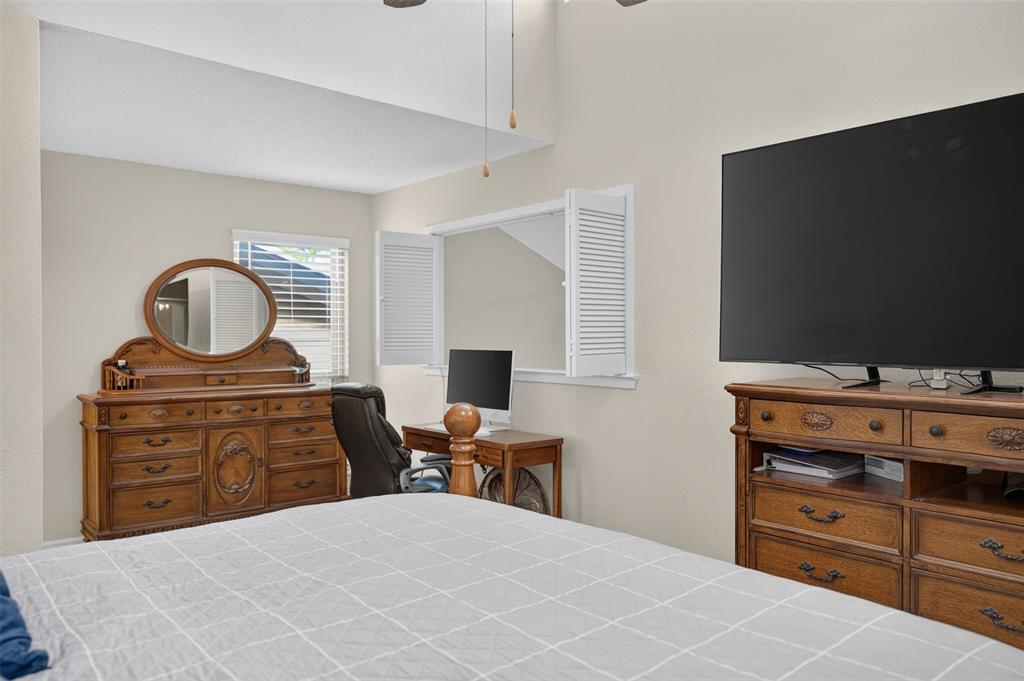 Vaulted ceiling with an integrated ceiling fan and interior louvered shutters opening to an interior space