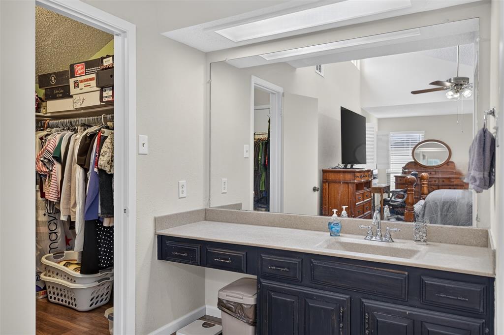 Vanity featuring a dark-toned cabinet, integrated countertop with a drop-in sink, chrome hardware, and a large-format mirror