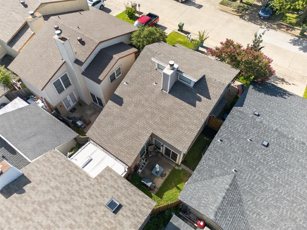 Aerial perspective of a suburban neighborhood featuring residential housing, mature trees, open green space, and paved road infrastructure
