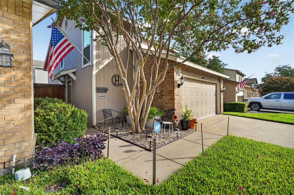 Multi-textured exterior featuring a combination of brick and vertical panel siding, an attached two-car garage, concrete driveway, and mature landscaping