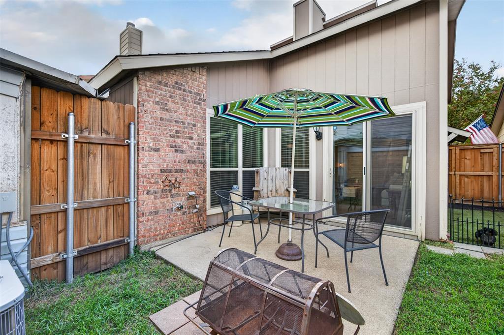 Concrete patio featuring a brick masonry accent wall, sliding glass door, and wood-panel privacy fencing