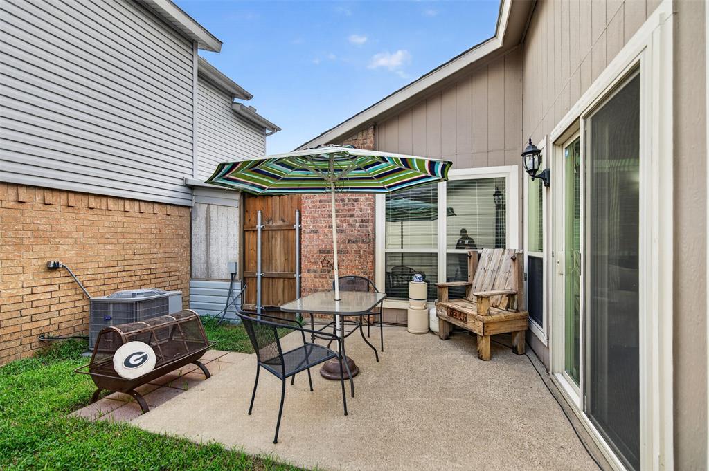 Concrete patio featuring a brick masonry accent wall, sliding glass door, and wood-panel privacy fencing
