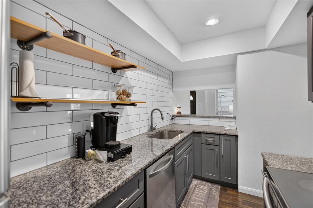 Kitchen featuring grey cabinetry, stone-finish countertops, stainless steel appliances, and wood-finish flooring