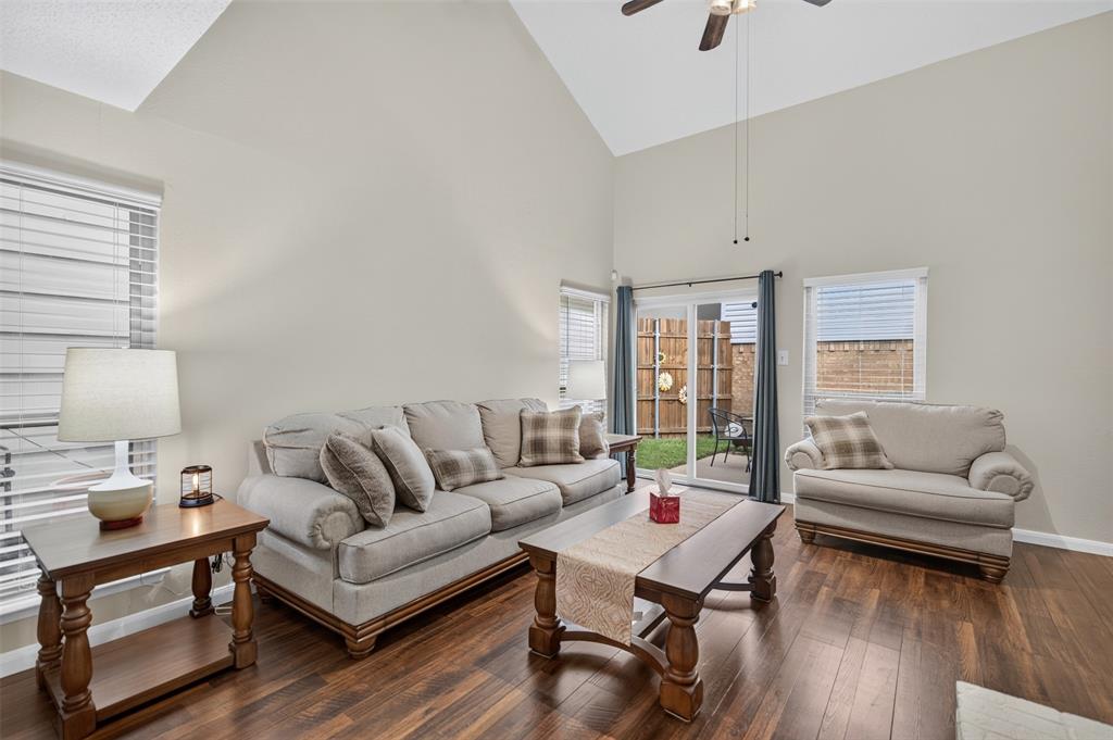 Vaulted ceilings, wood-finish flooring, and white-painted brick fireplace with a wood mantel