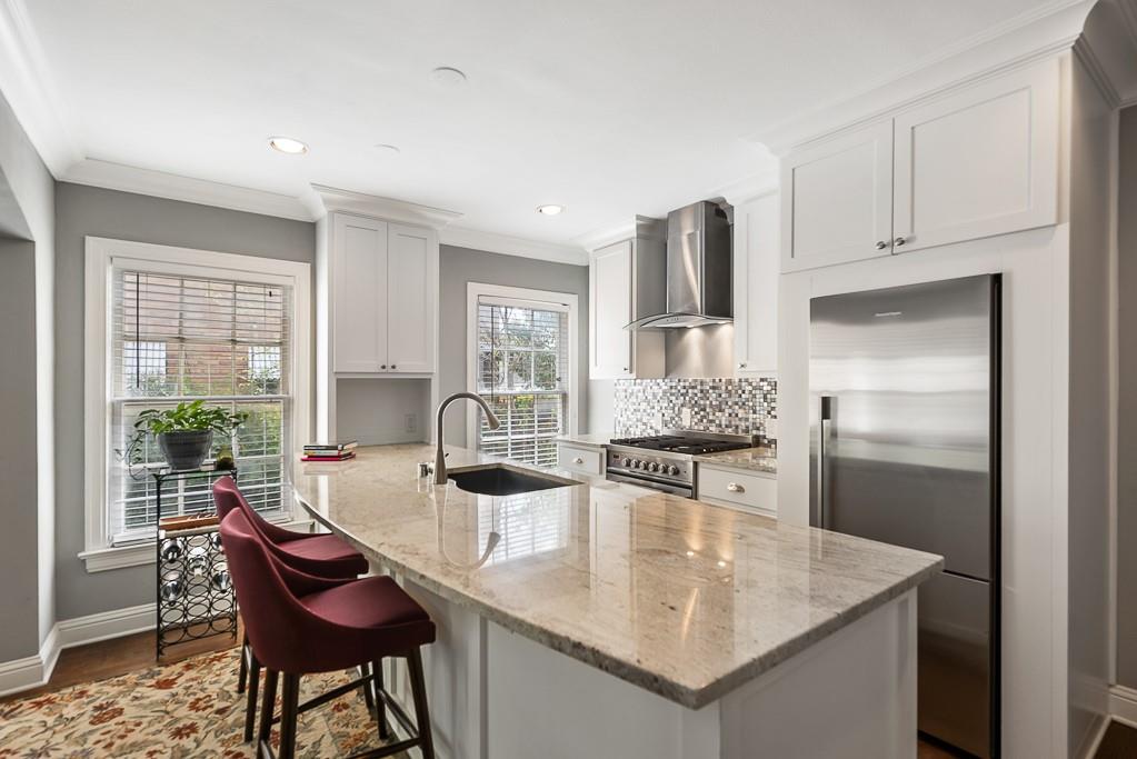 Kitchen featuring stone countertops, white cabinetry, stainless steel appliances, a mosaic tile backsplash, and recessed lighting