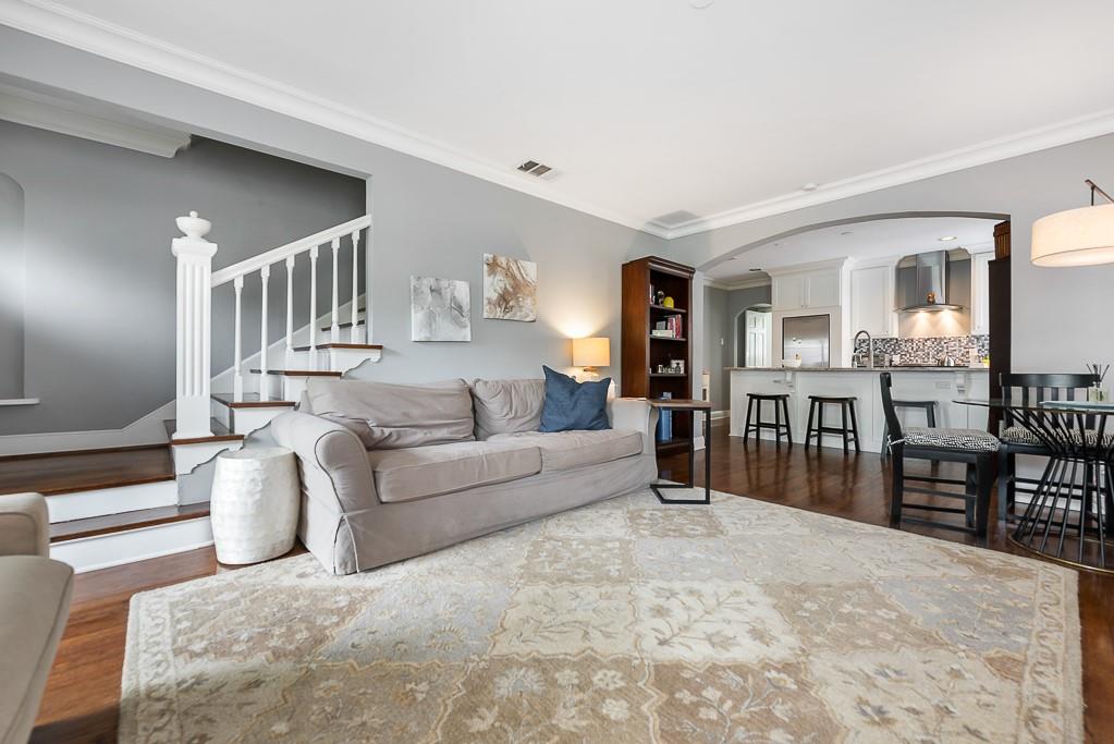 Open-concept interior featuring hardwood flooring, a staircase with a white balustrade, and a spacious archway