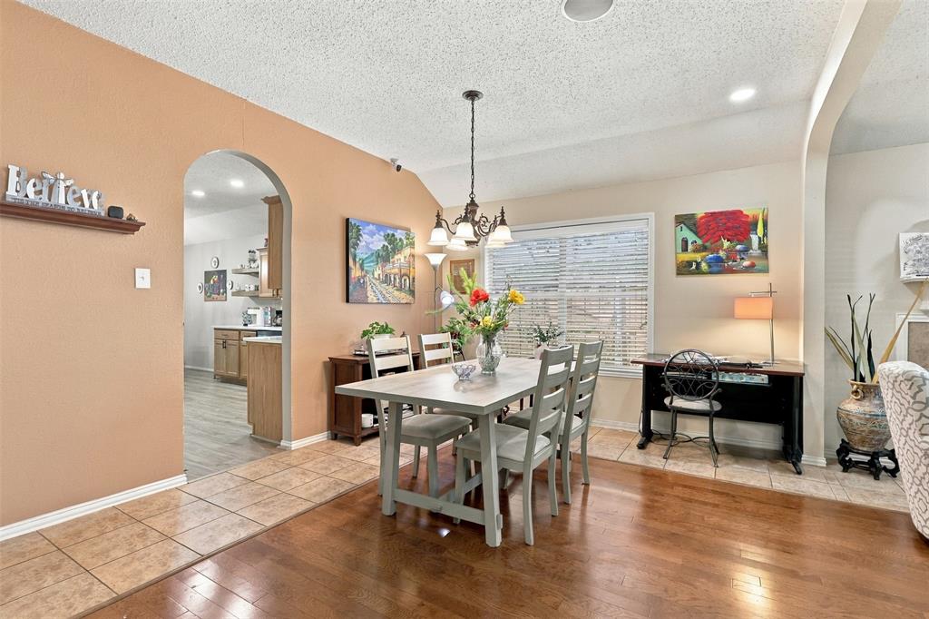 Dining area featuring wood-finish flooring, ceramic tile flooring, a multi-light chandelier, and arched wall openings