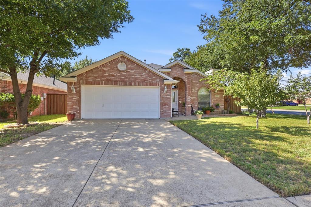 Single-story brick exterior featuring a front-facing attached garage, arched entryway, and mature landscaping Single-story brick exterior featuring a front-facing attached garage, arched entryway, and mature landscaping