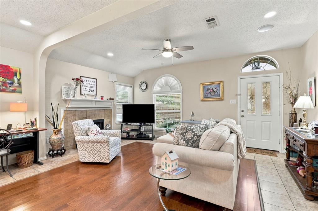 Living area featuring wood-finish flooring, a fireplace with tile surround, an arched entryway, recessed lighting, and a ceiling fan