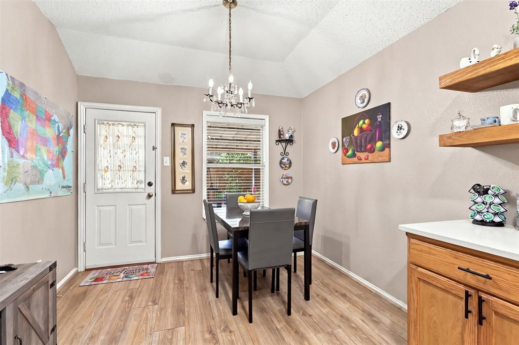 Vaulted ceiling with an overhead chandelier, wood-finish flooring, built-in wooden shelving, and a solid-core entry door with an integrated glass panel