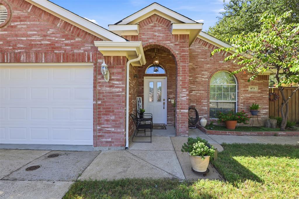 Brick exterior featuring a gabled roofline, arched entryway, white paneled front door with a transom window, and an attached two-car garage