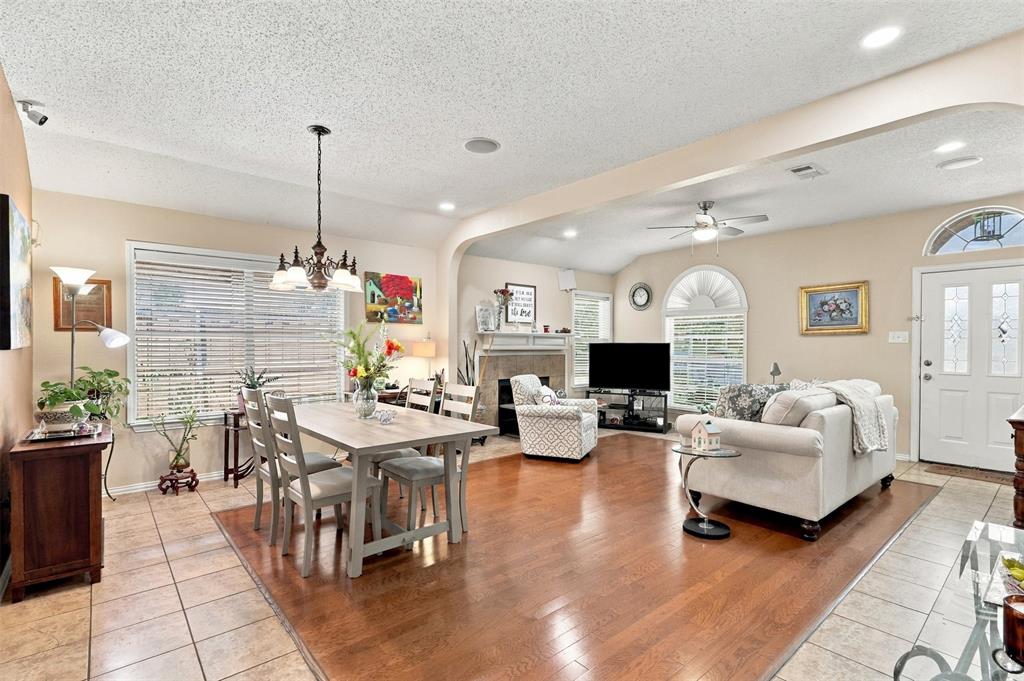 Open floor plan featuring wood-finish flooring, a fireplace with a stone-surround mantel, arched architectural detailing, and custom windows including a decorative transom