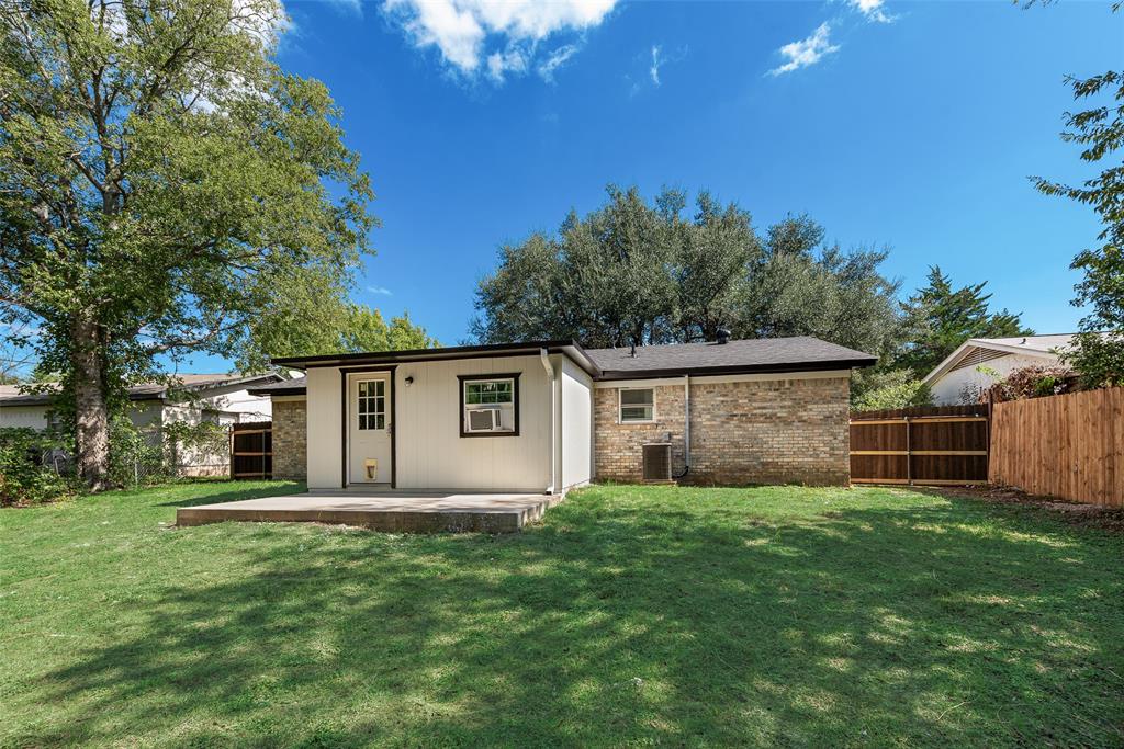 Rear exterior featuring a concrete patio, brick and vertical siding facade, and enclosed wooden fencing