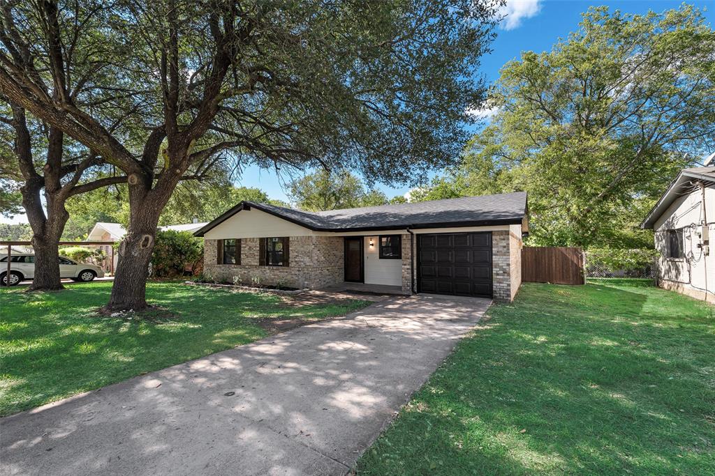 Single-story residence featuring a stone and siding exterior, asphalt shingle roof, attached garage, and mature trees on the lot